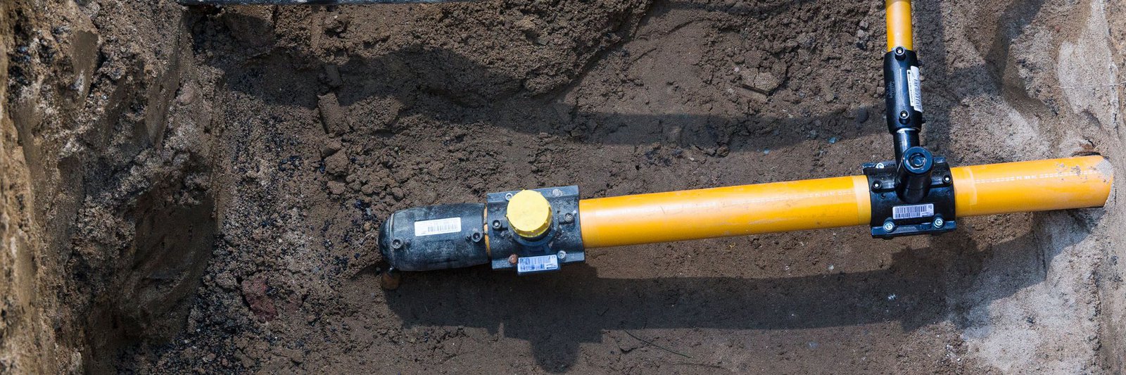 Blick in eine Baugrube von oben: Verlegung eines Gasnetzanschluss für ein Haus.