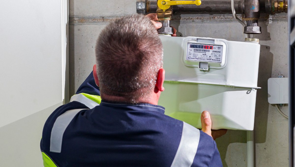 Ein Monteur tauscht turnusgemäß einen Gaszähler in einem Kellerraum und wird dabei von hinten fotografiert.fotografiert, steht
